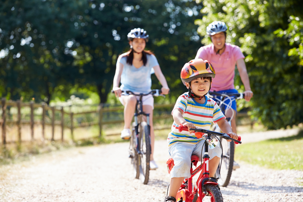 Two parents and their child ride bikes together outside