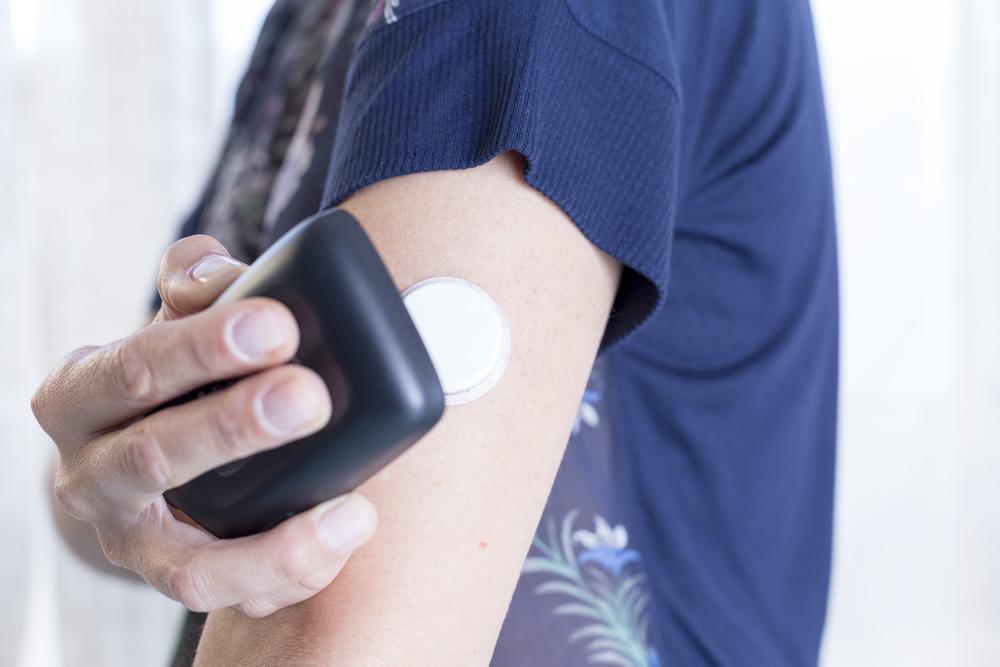 A person holds a receiver over their CGM device.