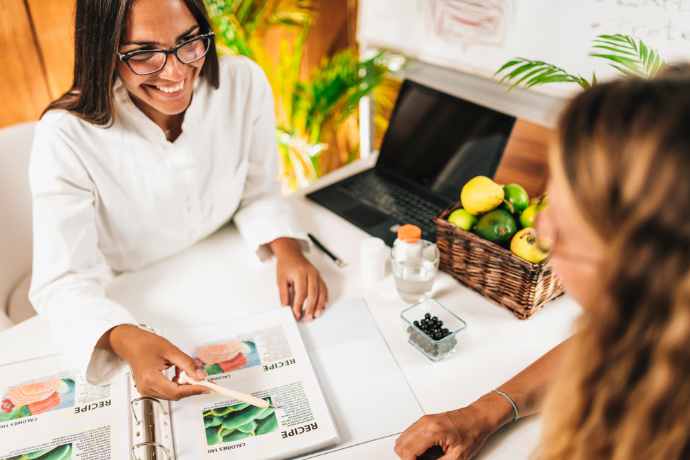 A diabetes dietitian and a client talk at a desk.